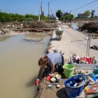 Una mujer lava vajilla en una zona inundada entre escombros, en Ca" di Lugo, un pequeño pueblo de Lugo (Ravenna), tras la crecida del río Santerno, en el norte de Italia, el 23 de mayo de 2023.