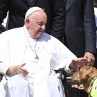 El Papa Francisco acaricia a un perro guía durante la Audiencia General semanal en la Plaza de San Pedro en el Vaticano, el 31 de mayo de 2023.