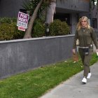 Evidencia. Una mujer pasea con su perro junto a un anuncio de alquiler de departamentos en Los Ángeles.