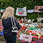 Una mujer mira flores, pancartas y bufandas cerca de la entrada a Villa San Martino en Arcore, donde el ataúd de Silvio Berlusconi fue llevado un día antes, cerca de Milán, en el norte de Italia, el 13 de junio de 2023.