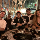 Shakira junto a Lewis Hamilton y un grupo de amigos celebrando en un restaurante.