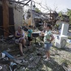 Una mujer y un niño entre los daños en el sitio alcanzado por la caída de escombros de un cohete, en la aldea de Stari Petrivtsi cerca de Kyiv (Kiev), Ucrania, el 16 de junio de 2023