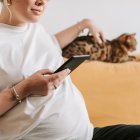 Una mujer embarazada acaricia a su gato.