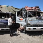 Las personas se paran junto a los camiones dañados en un mercado de verduras tras uno de los ataques.