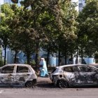 La gente pasa por delante de un coche incendiado en la avenida Pablo Picasso tras una noche de disturbios civiles, en Nanterre, cerca de París, Francia, el 28 de junio de 2023.