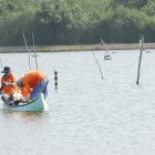 Trabajo. Dos personas en sus labores en una piscina de camarón.