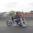 Ocupantes de moto movilizan una escalera metálica.