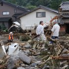 Personas observan los daños sufridos en las casas por las inundaciones y deslizamientos causados por las lluvias en Kurume, Japón.