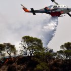 Un avión de extinción de incendios arroja agua para extinguir un incendio forestal que está quemando una zona forestal frente a las instalaciones de la refinería de Motor Oil, cerca de Loutraki, Grecia.