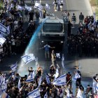 Policías utilizan un cañón de agua para intentar mover a las personas que bloquean la autopista Begin mientras continúan las protestas en todo el país tras la aprobación por el parlamento israelí o Knesset de un proyecto de ley que limitaría los poderes del Tribunal Supremo.