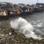 Un hombre se ve sorprendido por una ola mientras rescata materiales desperdigados por la orilla en Manila Bay, Filipinas, este miércoles.
