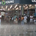 Turistas extranjeros se ven atrapados en una lluvia repentina en la calle Myeongdong en Seúl, Corea del Sur, el 31 de julio de 2023, en medio de una alerta de ola de calor.