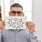Middle east man with beard holding banner with swear words angry and mad screaming frustrated and furious, shouting with anger. rage and aggressive concept.
