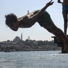 En la imagen de archivo, una persona se sumerge en las aguas del Bósforo para refrescarse, con la mezquita de Süleymaniye al fondo, en Estambul, Turquía.