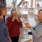 Artesanías. Adolfo Idrovo, investigador y artesano enseña a dos turistas, sus habilidades con los silbatos.