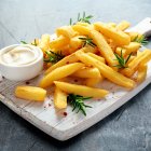 Homemade Baked Potato Fries with Mayonnaise and rosemary on white wooden board
