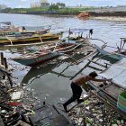 Un pescador fue registrado este 28 de agosto al mover una embarcación rodeada de materiales arrastrados por la corriente, tras el paso del supertifón Saola, en un pueblo pesquero de la ciudad de Paranaque (Metro Manila, Filipinas)