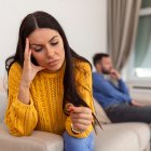 Stressed wife holding her wedding ring worried about breakup or divorce, avoid talking with husband after fight, anxious couple ignore each other. Frustrated sad wife taking off the wedding ring