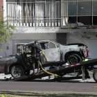 Un policía carga en una grúa los restos de un carro bomba que explotó en los exteriores del edificio del Servicio Nacional de Atención Integral a Personas Privadas de Libertad (SNAI), en Quito (Ecuador).