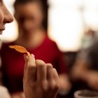 Close up of young woman eating tortilla chips while having fun with her friends in a tavern.