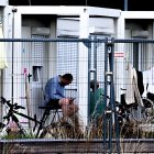 Un refugiado se sienta frente a contenedores usados como casas de acogida en el antiguo aeropuerto de Tegel.