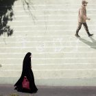 Imagen de archivo de una mujer con velo que pasa junto a una pared con un soldado iraní pintado en ella en una calle de Teherán.