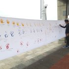 Personas acuden para dejar su huella de la mano en colores de la bandera sobre la lona y escribir un mensaje de paz