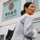 Una mujer camina este lunes frente a un banco en Pekín.
