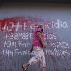 una mujer al caminar frente a un aviso pintado en una pared en contra del femicidio en Honduras, en una calle de Tegucigalpa.