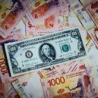 Fotografía de archivo que compara billetes de pesos argentinos con un billete de 100 dolares estadounidenses.