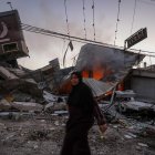 Una mujer palestina camina junto a una panadería destruida en el campo de refugiados de Al Nusairat, en el centro de la Franja de Gaza.