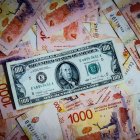 Fotografía de archivo de comparativa de billetes de pesos argentinos con un billete de 100 dolares estadounidenses.