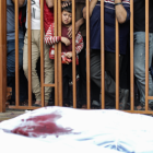 Un niño palestino observa tras unos barrotes los cadáveres de las víctimas cubiertos con sábanas en el hospital Nasser en Khan Yunis, al sur de la Franja de Gaza
