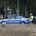 Milán. Un par de agentes empujan a un patrullero, afectado por el agua.