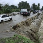 Tegucigalpa. Varios vehículos transitan por una carretera afectada por la creciente de agua en una quebrada.