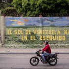 Un hombre conduce una moto frente a un mural que dice "El sol de Venezuela nace por el esequibo", el 2 de noviembre de 2023, en Caracas (Venezuela).