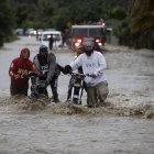 SAN JOSÉ DE OCOA (REPÚBLICA DOMINICANA), 04/10/2023.- Personas cruzan con dificultad la carretera que se encuentra inundada producto de las intensas lluvias, hoy en San José de Ocoa (República Dominicana). Una persona está desaparecida, al menos 1.522 fueron desplazadas de sus hogares y un puente colapsó debido a las intensas lluvias en la República Dominicana, que han llevado a las autoridades a decretar la alerta en 30 de las 32 provincias del país, 11 en nivel rojo. EFE/Orlando Barría