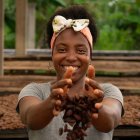 Fotografía cedida hoy por Ayuda en Acción que muestra a una mujer mientras deja caer granos de cacao cultivado de forma orgánica y ningún químico, en Tumaco, Nariño (Colombia). EFE/AYUDA EN ACCIÓN/Gabriel Ferrero