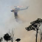 Un helipcótero lanza agua sobre una zona afectada por el fuego, que comenzó en una plantación de pinos en el barrio de Gnangara, un área rural y residencial del noreste de Perth.