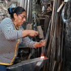 Lucila con el combo y cincel golpea una manija contra el yunque.