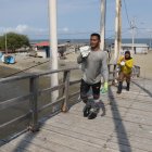 Puente. Al puente le faltan varias tablas, otras están levantadas, mientras que largos tramos de la barandilla se han roto y caído y las vigas de la desvencijada estructura están oxidadas y sueltas.