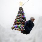 Una mujer camina junto a un árbol de Navidad cubierto de nieve tras una fuerte nevada en Moscú, Rusia, el 15 de diciembre de 2023.