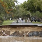 Un grupo de personas observan la vía interrumpida, a causa de las lluvias torrenciales que caen desde hace cinco días.