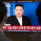 Dos personas viendo en televisión al líder norcoreano Kim Jong-un.