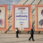 Dos hombres pasan frente a los retratos del líder supremo de Irán, Ali Jameneí, y ayatolá Ruholá Jomeiní durante la conmemoración del 44º aniversario del triunfo de la Revolución Islámica en Teherán.