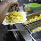 Local. El ayudante en uno de los locales, especializado en la salchipapa y papipollo, fríe la papa.