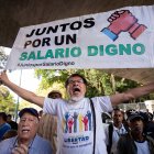 Un trabajador carga una pancarta que dice "juntos por un salario digno" durante una protesta para exigir aumento salarial y de pensiones, hoy, en Caracas (Venezuela).