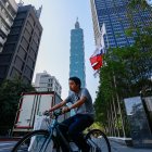 Un ciclista circula junto a una bandera de Taiwán en una calle desde la que se ve el rascacielos Taipei 101, el 12 de enero de 2024, un día antes de las elecciones presidenciales.