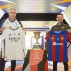 Los entrenadores Carlo Ancelotti (i) y Xavi (d) junto al trofeo de la Supercopa de España.