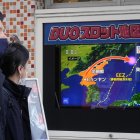 Imagen de unos viandantes observando en un monitor un lanzamiento de un misil balístico norcoreano.